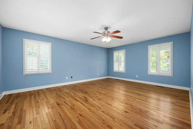 empty room featuring baseboards, ceiling fan, visible vents, and hardwood / wood-style floors