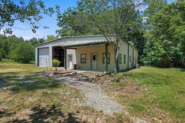 view of front of house with driveway, an outbuilding, cooling unit, and a front yard