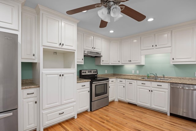 kitchen featuring appliances with stainless steel finishes, white cabinets, a sink, light wood-type flooring, and under cabinet range hood