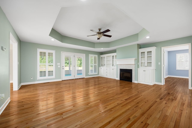 unfurnished living room featuring hardwood / wood-style flooring, baseboards, a fireplace, and a tray ceiling