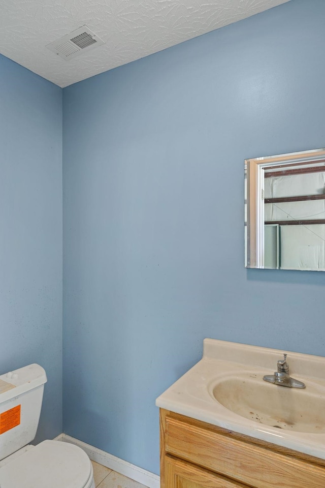 half bath featuring visible vents, toilet, vanity, baseboards, and tile patterned floors