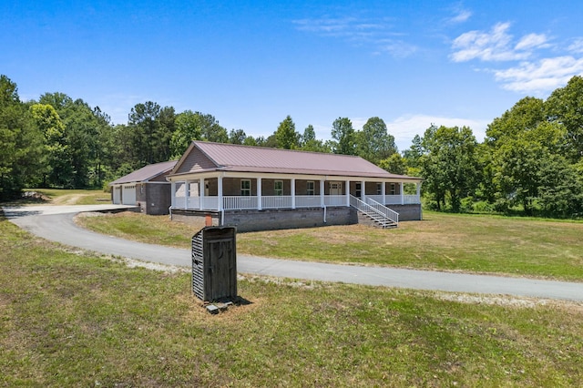 view of front of property featuring a garage, covered porch, metal roof, and a front yard