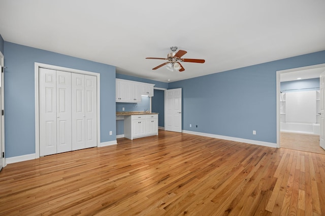 unfurnished bedroom with ceiling fan, light wood-type flooring, built in study area, and baseboards