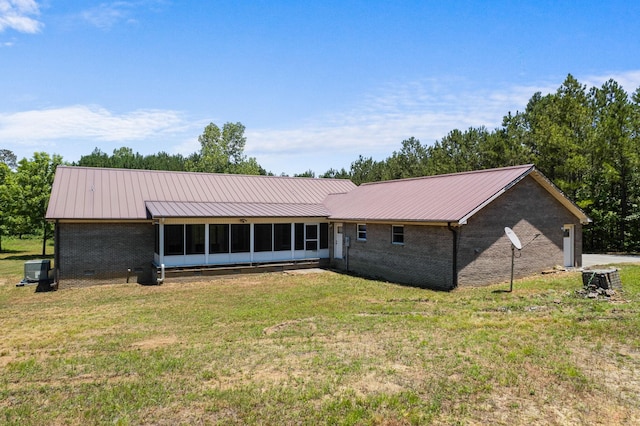 rear view of property featuring metal roof, brick siding, a sunroom, a yard, and crawl space