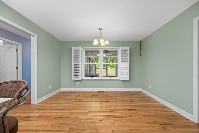 dining area with light wood-type flooring, baseboards, and a notable chandelier