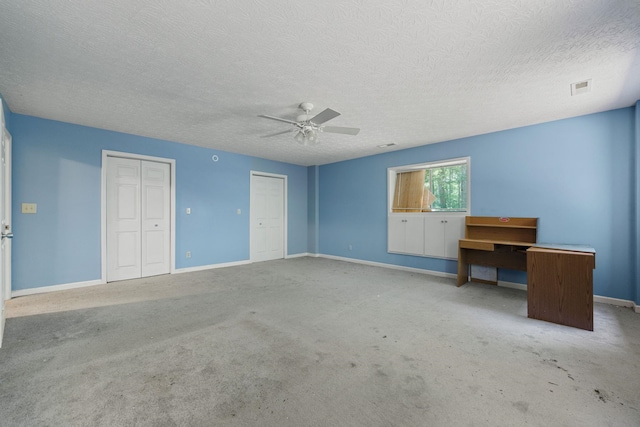 unfurnished bedroom featuring baseboards, visible vents, a ceiling fan, carpet flooring, and multiple closets