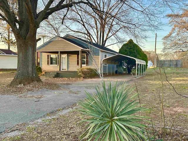 bungalow-style home featuring dirt driveway and a detached carport