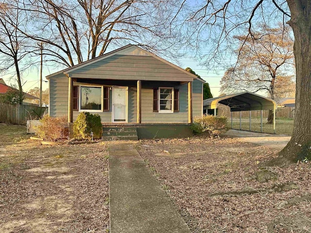 bungalow-style house featuring covered porch, fence, and a carport