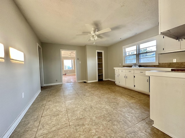 kitchen featuring light countertops, a ceiling fan, white cabinets, a textured ceiling, and baseboards