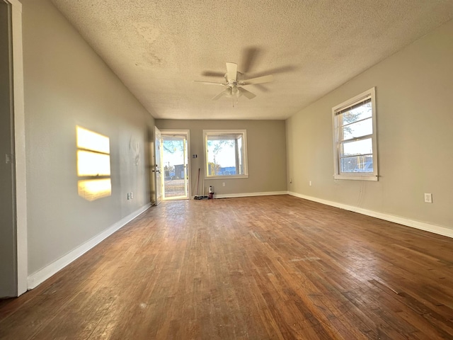 spare room featuring a ceiling fan, dark wood-style flooring, a textured ceiling, and baseboards