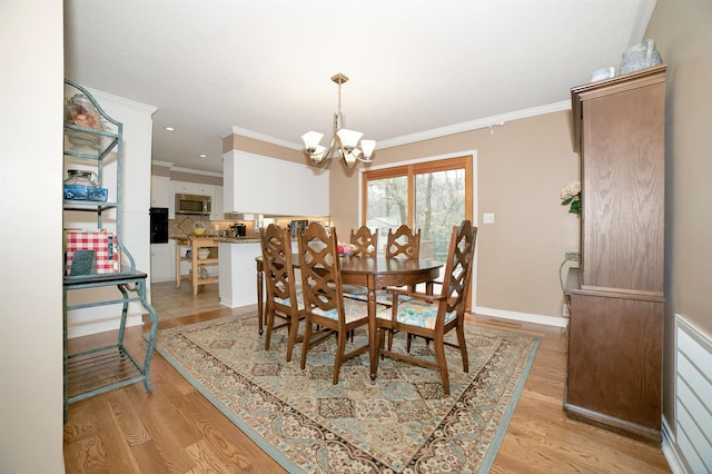 dining area featuring baseboards, light wood-style flooring, an inviting chandelier, and crown molding