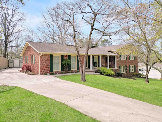view of front of house with driveway, a front yard, an outdoor structure, and brick siding
