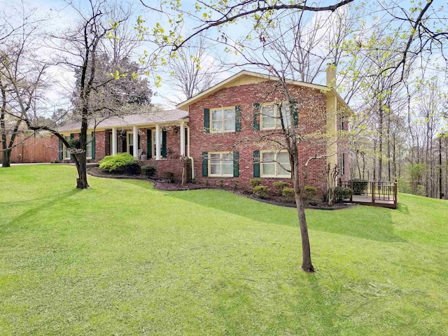 split level home with a chimney, a front yard, and brick siding