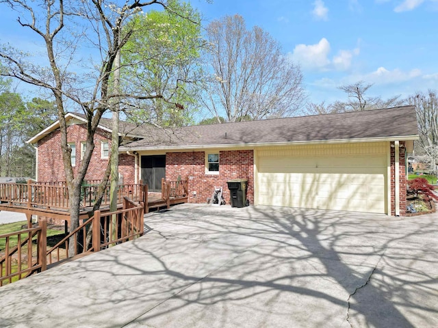 exterior space featuring brick siding, driveway, a garage, and a wooden deck