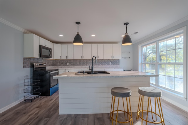 kitchen with stainless steel electric stove, white cabinets, sink, and a center island with sink