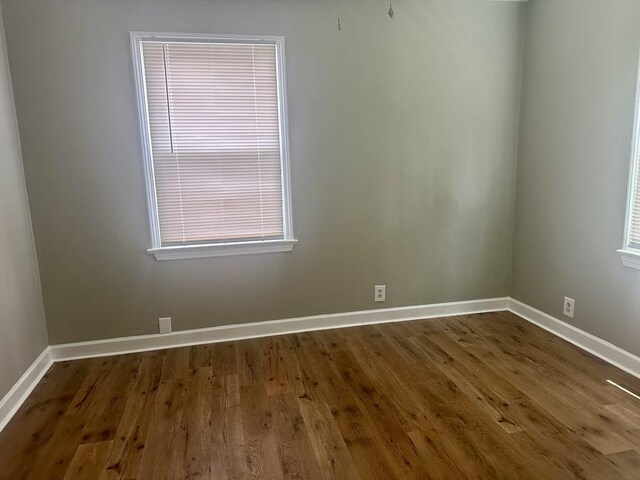  - empty room with baseboards and dark wood-style floors