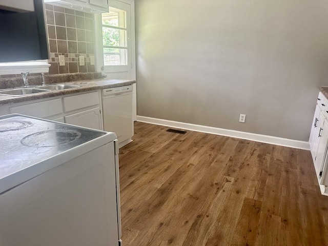  - kitchen featuring white appliances, white cabinetry, wood finished floors, and decorative backsplash
