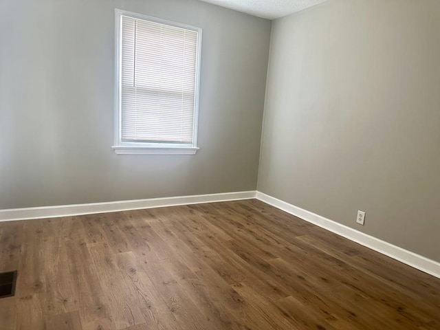  - empty room with baseboards and dark wood-type flooring