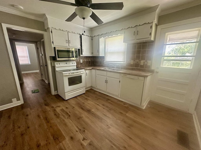  - kitchen with white appliances, crown molding, white cabinets, backsplash, and plenty of natural light