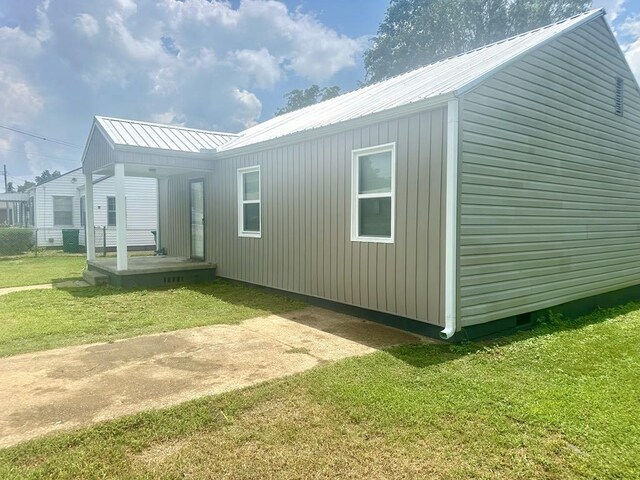  - view of property exterior featuring a yard and a metal roof