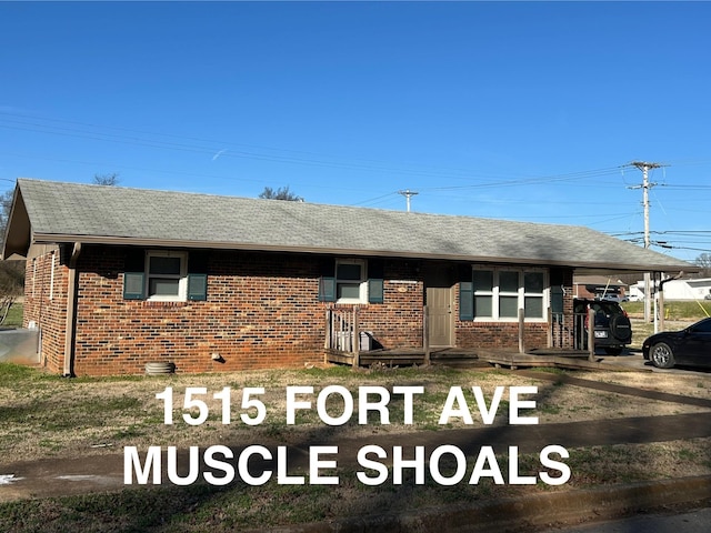 ranch-style home with a shingled roof, brick siding, and an attached carport