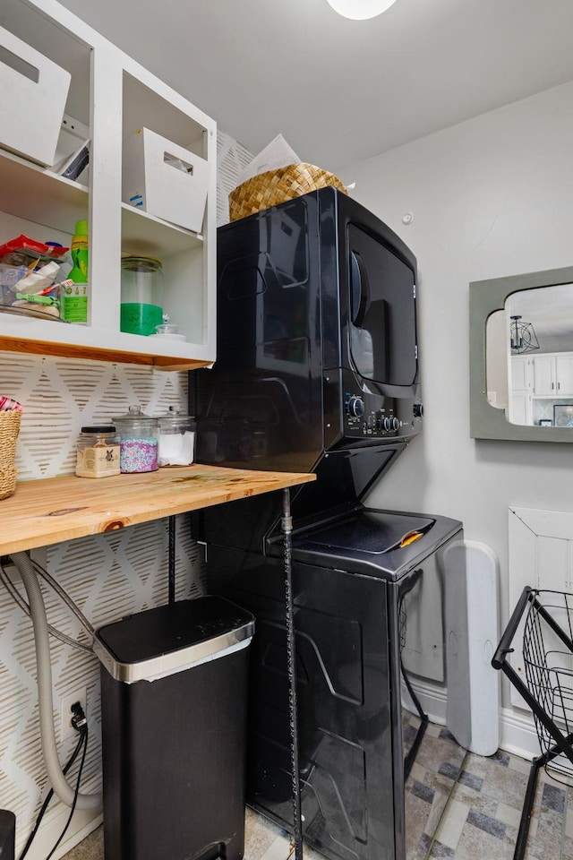 laundry area with baseboards, stacked washing maching and dryer, and laundry area