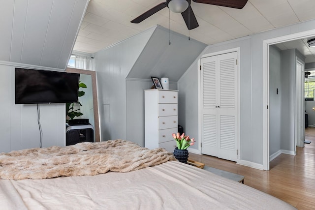 bedroom with a closet, a ceiling fan, vaulted ceiling, wood finished floors, and baseboards