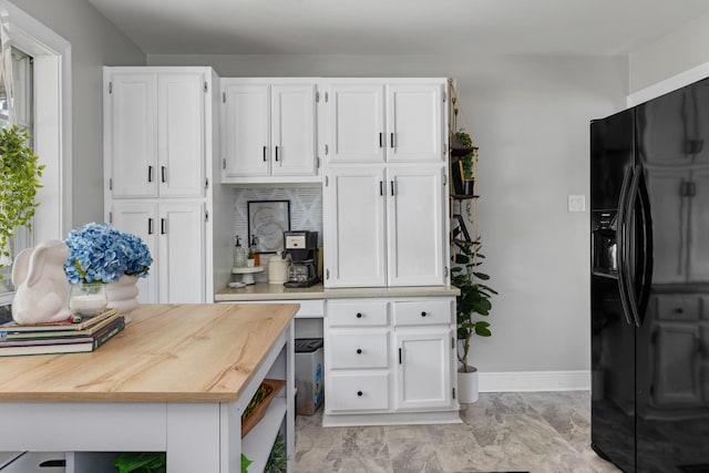 kitchen featuring white cabinets, baseboards, black fridge, butcher block countertops, and marble finish floor