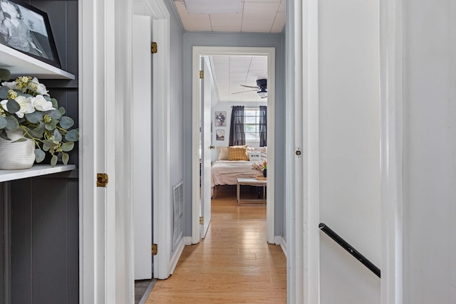 hall featuring light wood-type flooring, a drop ceiling, attic access, an upstairs landing, and baseboards