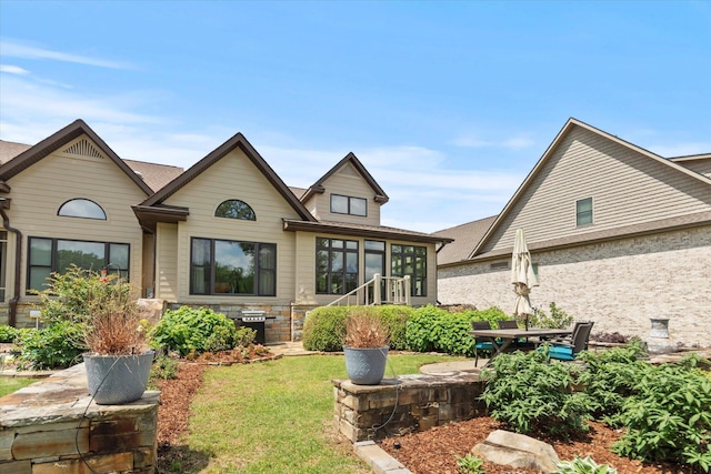  - back of property featuring a yard, a sunroom, and a patio