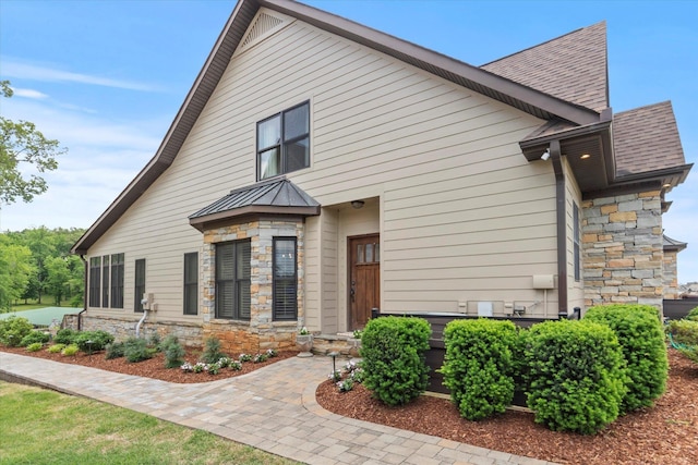  - view of side of property with stone siding, a standing seam roof, and metal roof