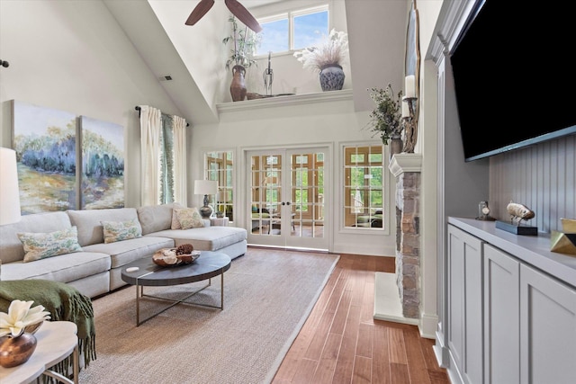  - living area featuring a high ceiling, light wood-type flooring, ceiling fan, french doors, and baseboards