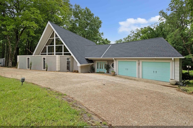 - a-frame home with concrete driveway, a shingled roof, and an attached garage