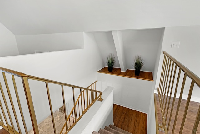  - stairs featuring wood finished floors and vaulted ceiling