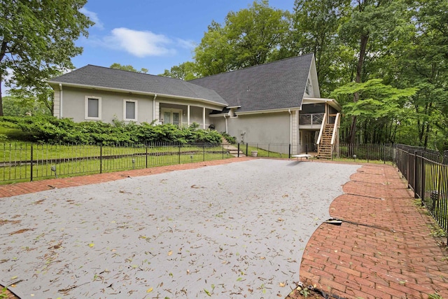  - view of front of property featuring stairway, a sunroom, driveway, and stucco siding