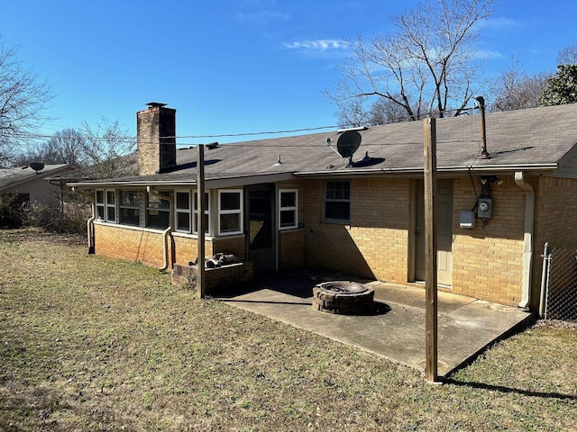 rear view of property with an outdoor fire pit, a sunroom, a chimney, a patio area, and brick siding