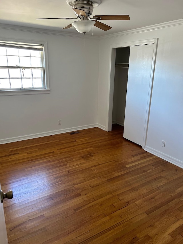 unfurnished bedroom featuring ornamental molding, wood finished floors, visible vents, and baseboards