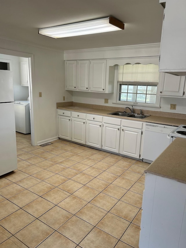 kitchen featuring white appliances, washer / dryer, white cabinets, ornamental molding, and a sink