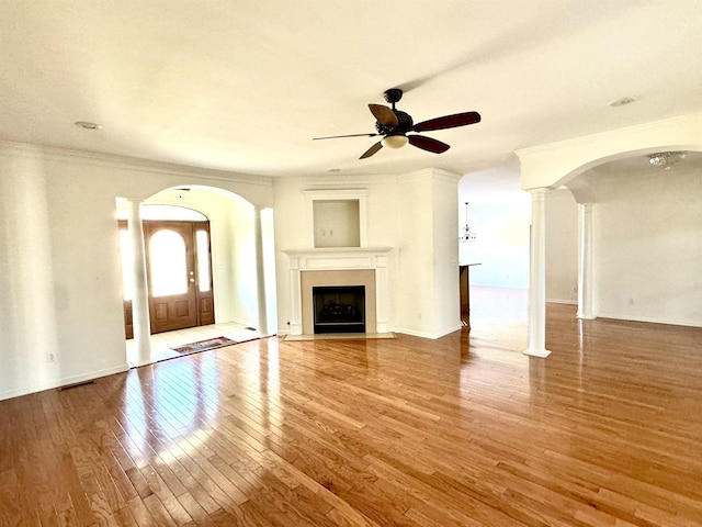 unfurnished living room featuring hardwood / wood-style flooring, ceiling fan, crown molding, and decorative columns