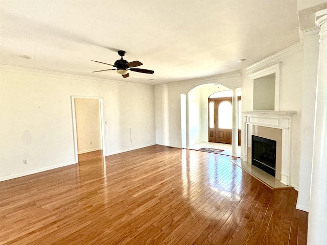 unfurnished living room featuring hardwood / wood-style floors, ceiling fan, crown molding, and decorative columns