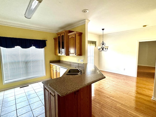 kitchen with kitchen peninsula, ornamental molding, sink, dishwasher, and a chandelier