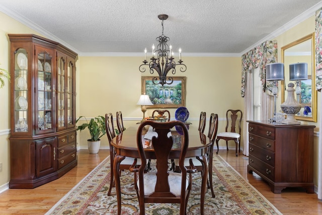 dining room with ornamental molding, light hardwood / wood-style floors, a textured ceiling, and an inviting chandelier