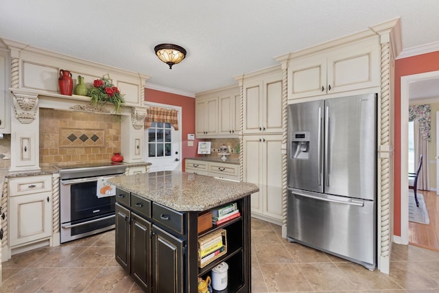 kitchen with a center island, backsplash, cream cabinets, appliances with stainless steel finishes, and light stone counters