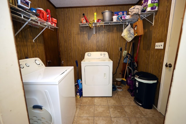 laundry room with light tile patterned floors, separate washer and dryer, and wood walls