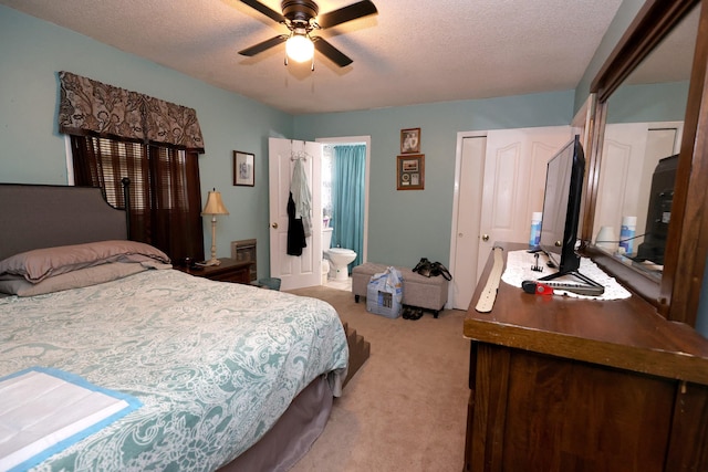 bedroom featuring ceiling fan, ensuite bathroom, light carpet, and a textured ceiling