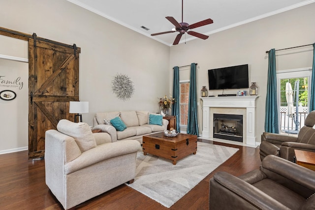  - living room with ceiling fan, wood finished floors, baseboards, ornamental molding, and a barn door