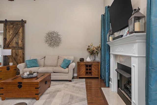  - living area featuring wood finished floors, a barn door, a fireplace with flush hearth, and baseboards