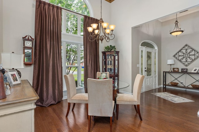 - dining room with a towering ceiling, dark wood-style flooring, a chandelier, and crown molding