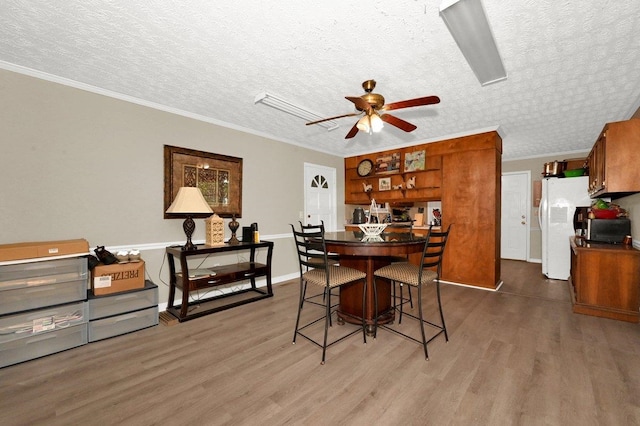 dining room featuring ceiling fan, dark wood-type flooring, a textured ceiling, and ornamental molding