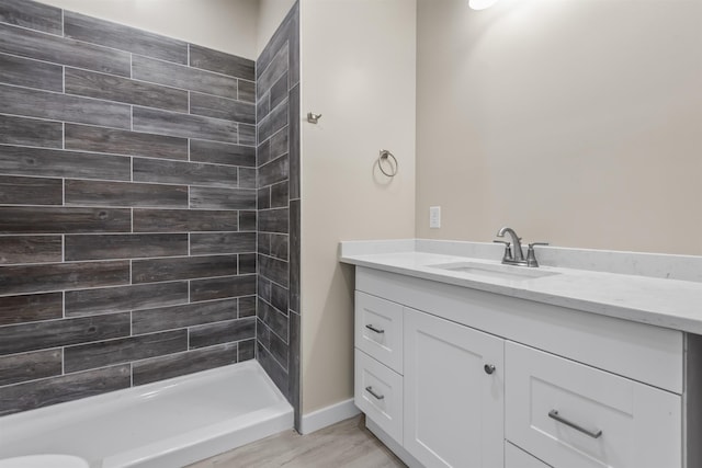 bathroom featuring hardwood / wood-style floors, vanity, and tiled shower